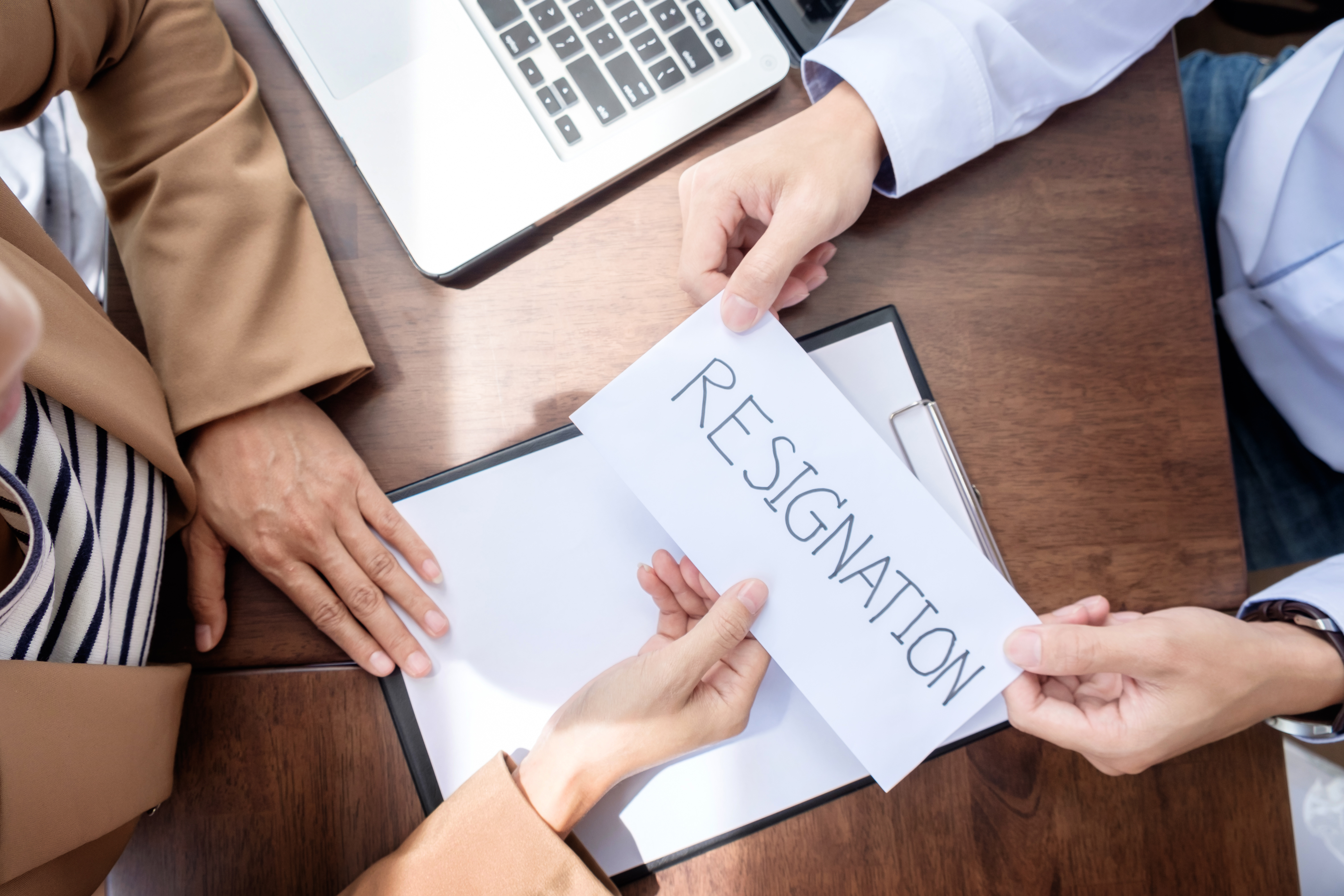 Hand Of A Businessman Hands Over A Resignation Letter On A Woode 